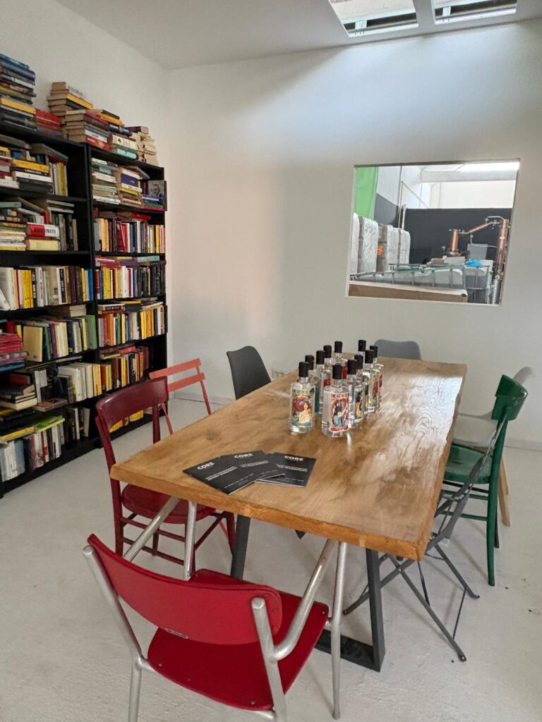 Sala degustazione di Core Distillery a Roma, con tavolo, bottiglie di gin e libreria